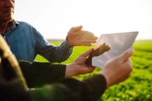 Pessoa visualizando uma Cédula de Produto Rural (CPR) em um tablet ao ar livre, em um campo verde sob luz solar, promovendo negociações e investimentos rurais.
