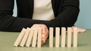 Pessoa impedindo a procriação de uma série de dominós que estão caindo, simbolizando controle ou resistência.