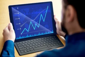Pessoa analisando gráficos de crescimento financeiro em um tablet, indicando sucesso nos investimentos e aumento de lucros.