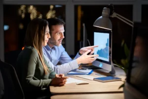 Homens e mulheres trabalhando juntos em um escritório, analisando dados de um gráfico de crescimento no computador, em ambiente de negócios.