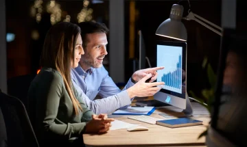 Homens e mulheres trabalhando juntos em um escritório, analisando dados de um gráfico de crescimento no computador, em ambiente de negócios.