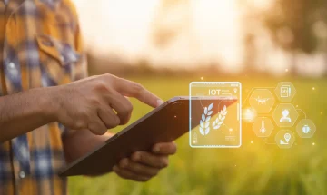 Pessoa usando um smartphone ao ar livre com ícones de tecnologia e IoT flutuando ao redor, incluindo uma tela com folhas de louro e elementos de agricultura digital.